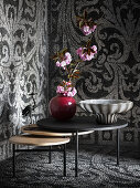 Red ceramic vase and opal glass bowl on set of nesting tables in corner of room with mosaic walls and floor