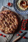 From above loaf of Ramazan pidesi placed near fresh tomatoes and spices on lumber tabletop