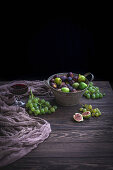 Fresh figs and grapes in a bucket and on rustic wooden table
