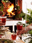 A couple toasting with red wine at a Christmas buffet in front of a fireplace