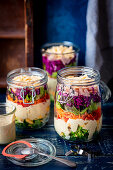 Layered salad in a jar - broccoli, eggs, sauce, peper, carrot, lettuce, purple cabbage, ham, cheese