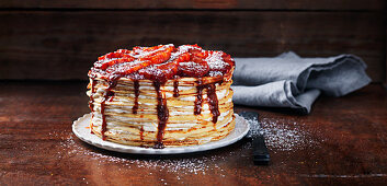 Pancake cake with jam, strawberries and icing sugar