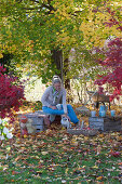 Upturned wine crates as a seating area under the maple tree, woman with a teacup, with Zula the dog