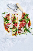 Pizza mit Prosciutto, Parmesan und Rucola