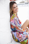 A young blonde woman wearing a brightly patterned summer dress