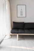 Simple futon sofa with black cushions in corner next to glass wall