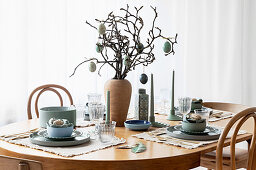 Table set simply in natural shades and decorated with branches and Easter eggs