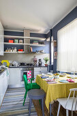 White kitchen cabinets and dark blue walls in kitchen-dining room