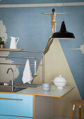 Sink unit with blue front against wall with artistic mural wallpaper
