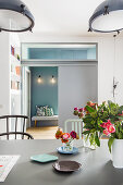 View across dining table through sliding doors with glass elements and into bedroom with blue wall