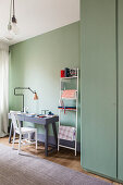 Desk next to stationary on metal ladder in room with mint-green walls