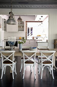 Dining table and chairs in front of open doorway leading into kitchen