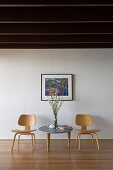 Coffee table and classic chairs below picture on white wall