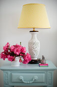 Table lamp with ceramic base and deep pink flowers on bedside table