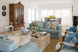 Blue sofas and chairs around coffee table and antique display case in living room