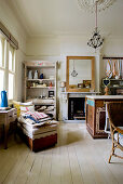 Couch in front of shelves and fireplace in shabby-chic, open-plan room