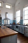 Stainless steel kitchen with frosted glass cabinets and pale blue tiled splashback