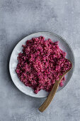 Rotes Quinoa mit Holzlöffel auf Teller