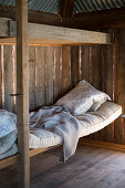 Simple sleeping area in rustic wooden cabin