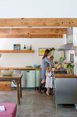 Kitchen with stainless steel cabinets and wooden worksurfaces in interior with wood-beamed ceiling