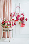 Bouquet of flowers on a chair behind it DIY advent calendar in white, red and pink