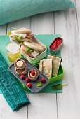 Picknick mit Kräuterkuchen, Bananen-Himbeer-Häppchen, Mortadella-Sandwiches und Bier