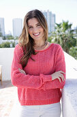 A young woman wearing a fuchsia jumper and white jeans