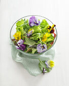Pflücksalat und Essblüten in einer Glasschüssel