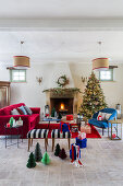 Christmas tree and blue and red furnishings in front of open fireplace