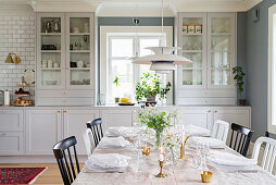 Festively set table in front of open-plan kitchen in country-house style