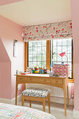 Desk below lattice window in room with pink walls