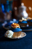 Perfectly decorated cupcake topped with blue icing and gold rose