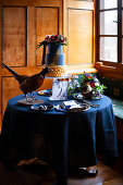 Ausgestopfter Fasan, Torte und Blumen auf blau gedecktem Tisch
