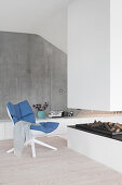 Easy chair next to open fireplace in front of concrete wall in architect-designed house