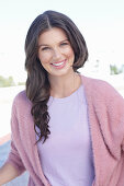 A young woman with long hair wearing a purple t-shirt and a wrap-around jumper