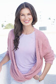 A young woman with long hair wearing a purple t-shirt and a wrap-around jumper