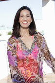 A brunette woman wearing a colourful beach dress