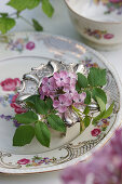 Lilac blossoms and rose petals in a silver egg cup