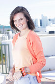 A young woman wearing an apricot top and cardigan