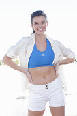 A young woman wearing a blue sports bra, a white shirt and shorts