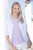 A young blonde woman wearing a purple t-shirt, a shirt and white trousers