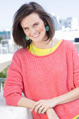 A young woman wearing large earrings, a fuchsia jumper and a yellow top