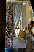 Ornate metal screen and antique armchair in stylish yellow parlour