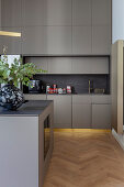 Island counter and golden baseboards in grey modern kitchen
