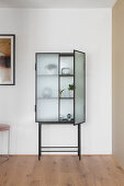 Objets d'art in glass-fronted cabinet with open door