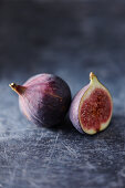 A whole and a half fresh fig on a gray background