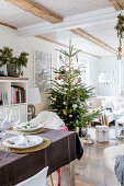 Gedeckter Tisch und Weihnachtsbaum im offenen Wohnraum