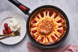 Cutting baked pie with strawberry in pan on table