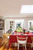 Dining table with red tablecloth below skylight in open-plan dining area