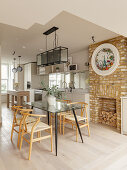 Glass dining table and brick fireplace in open-plan kitchen